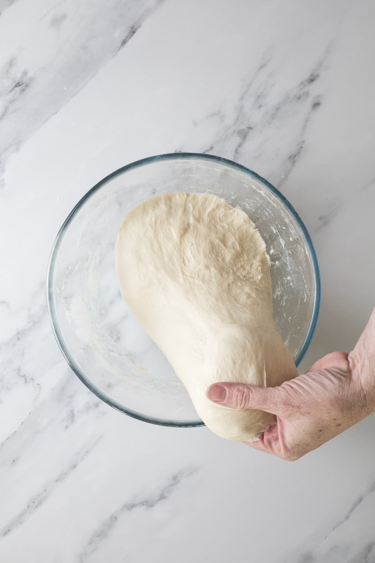 Hand stretching same day sourdough dough during the stretch and fold process.