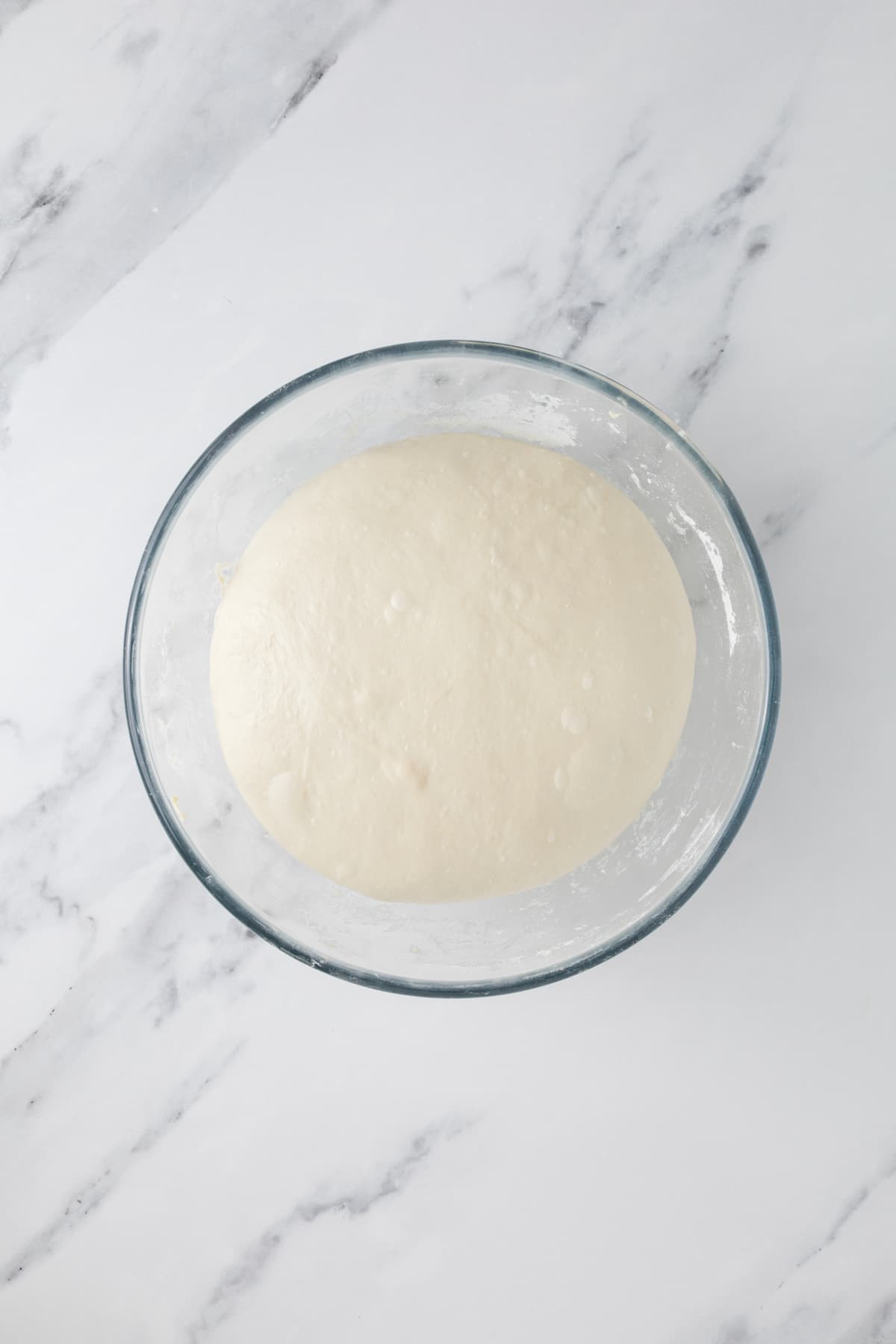Same day sourdough dough after resting in a glass bowl during bulk fermentation.