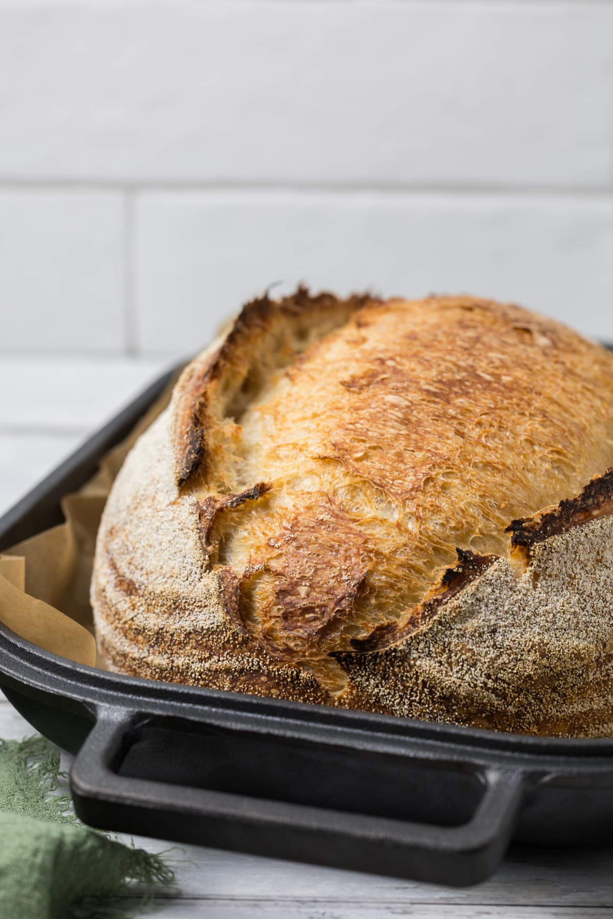 Freshly baked same day sourdough bread in a cast iron baker with a deeply golden crust.