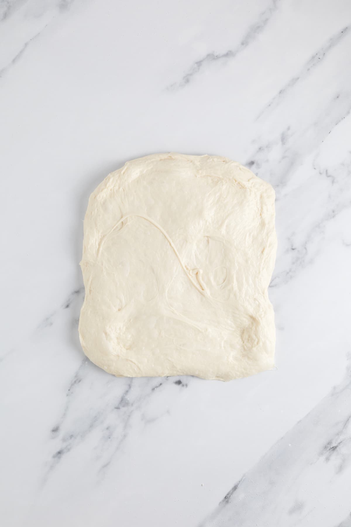 Small batch sourdough bread dough stretched flat during shaping before forming into a loaf.