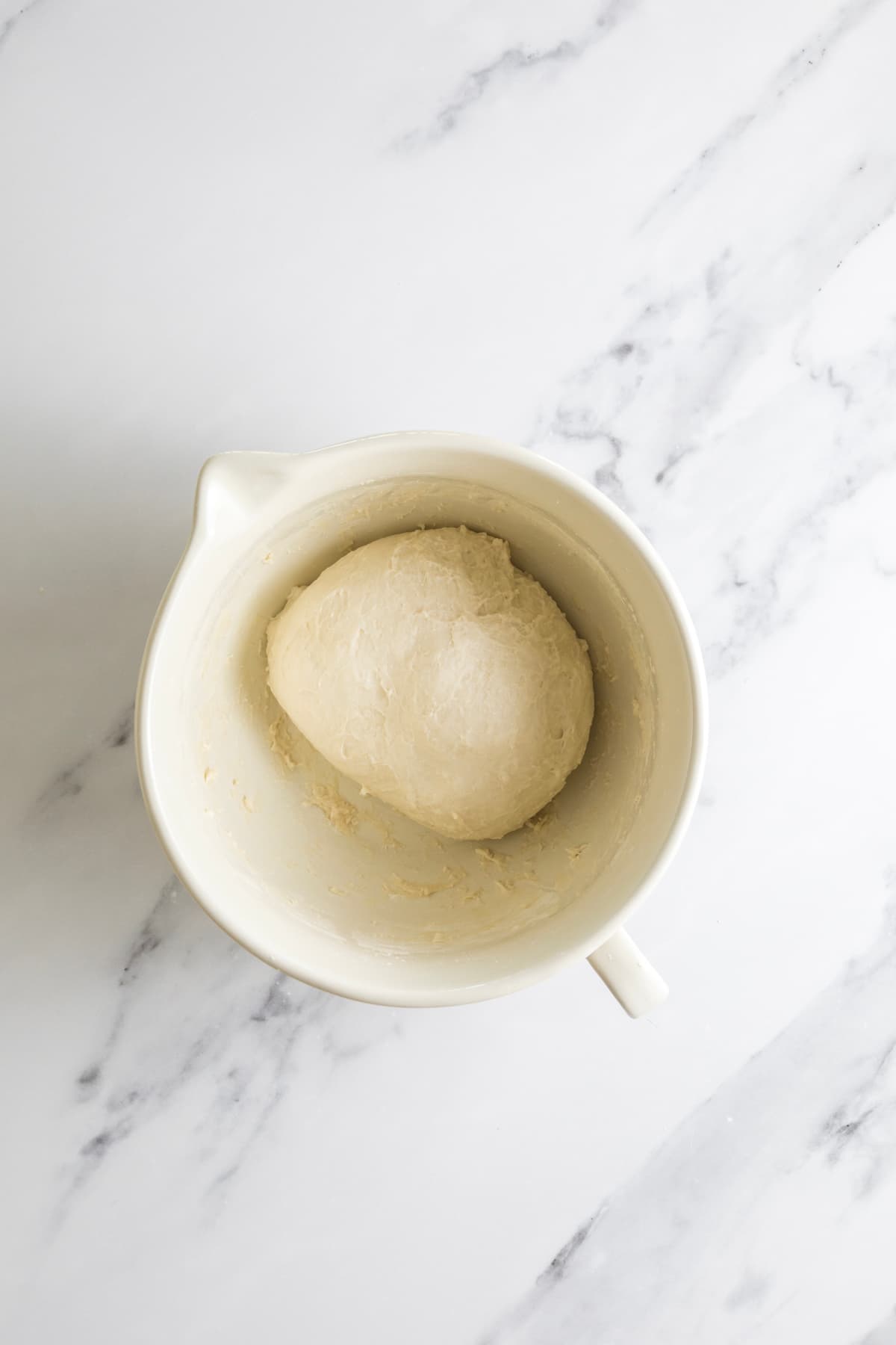 Smooth small batch sourdough dough ball after kneading in a ceramic bowl.