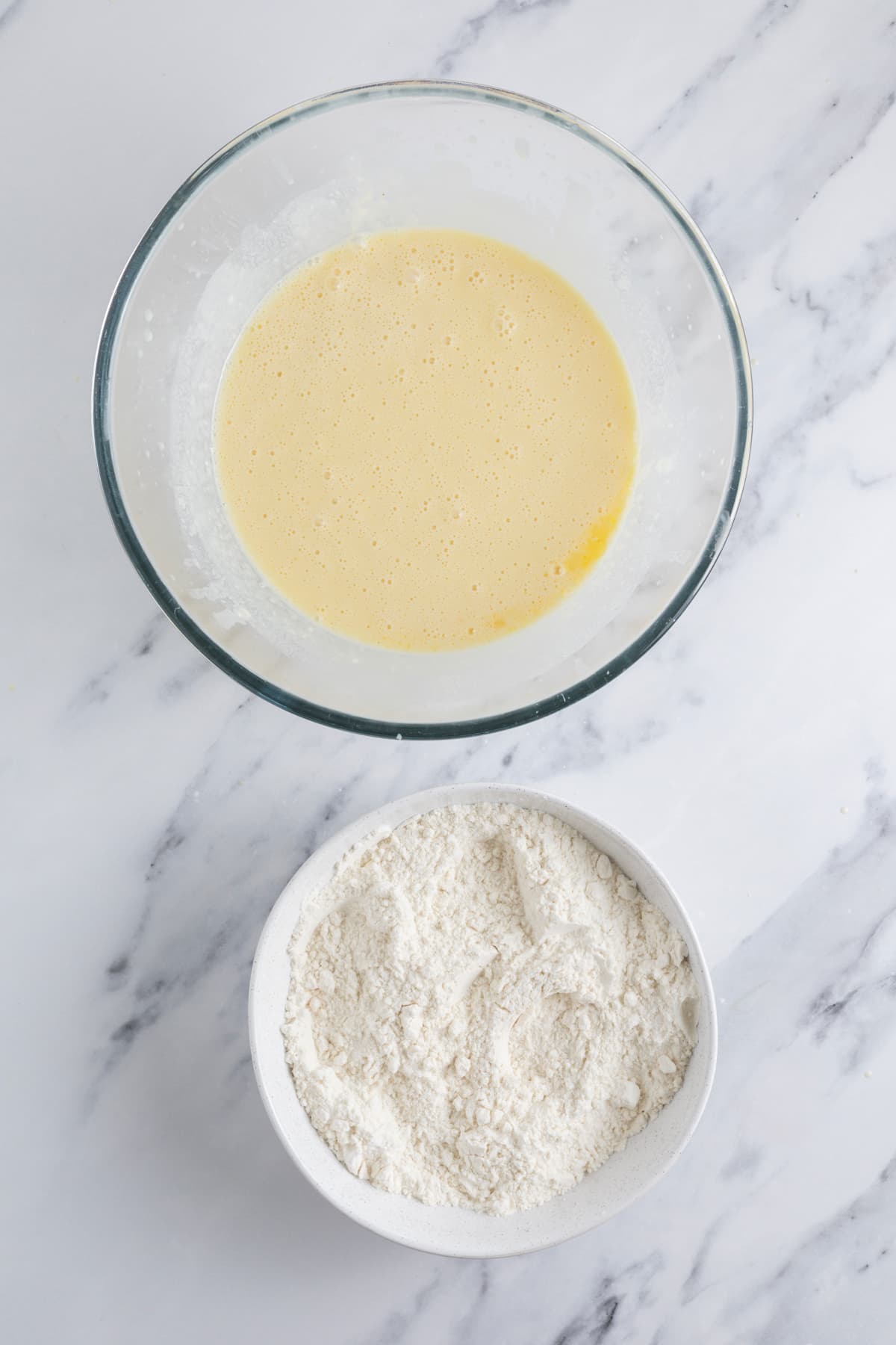 Wet ingredients for sourdough discard waffles beside a bowl of dry ingredients on the counter.