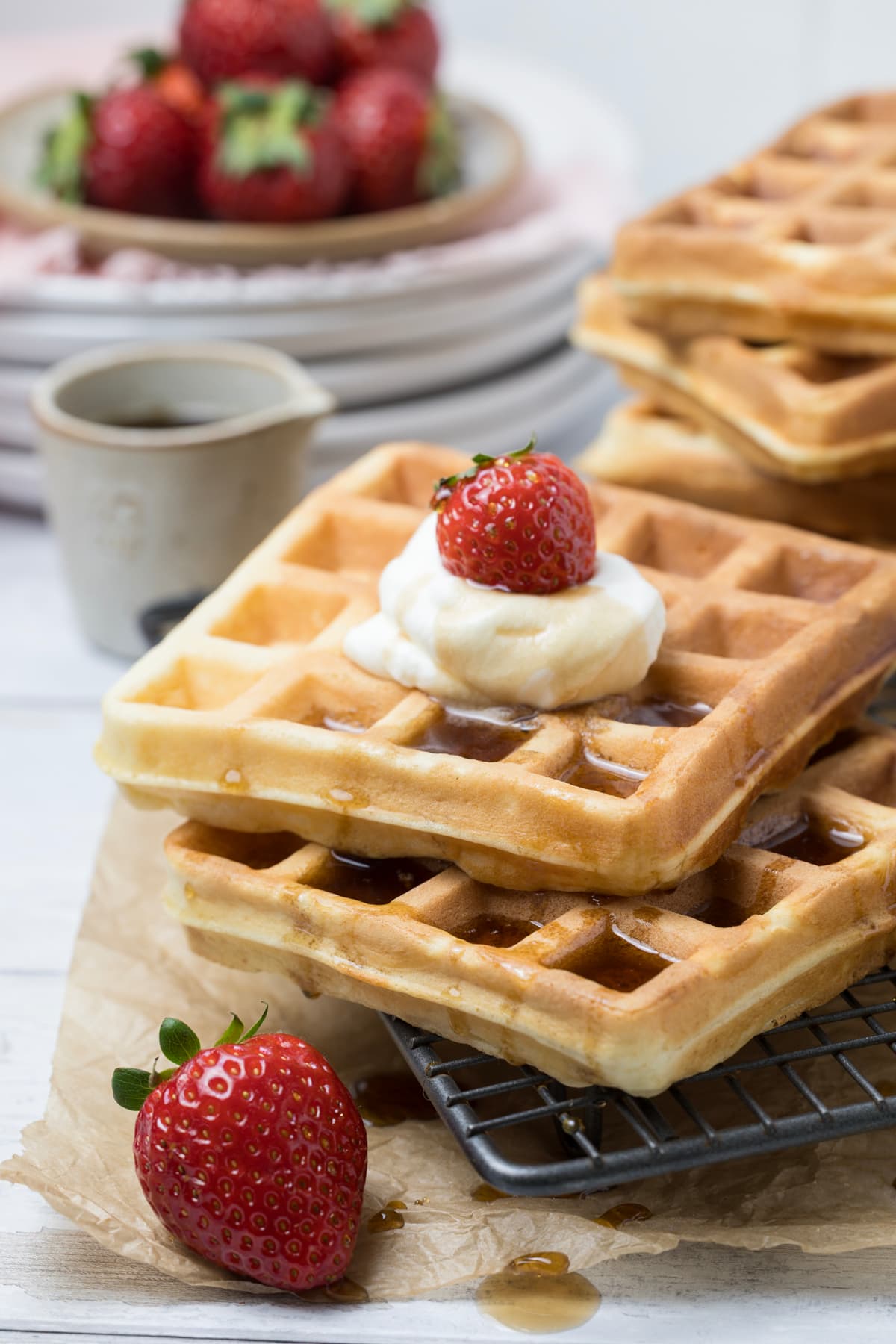 Sourdough discard waffles topped with whipped cream, fresh strawberries, and maple syrup.