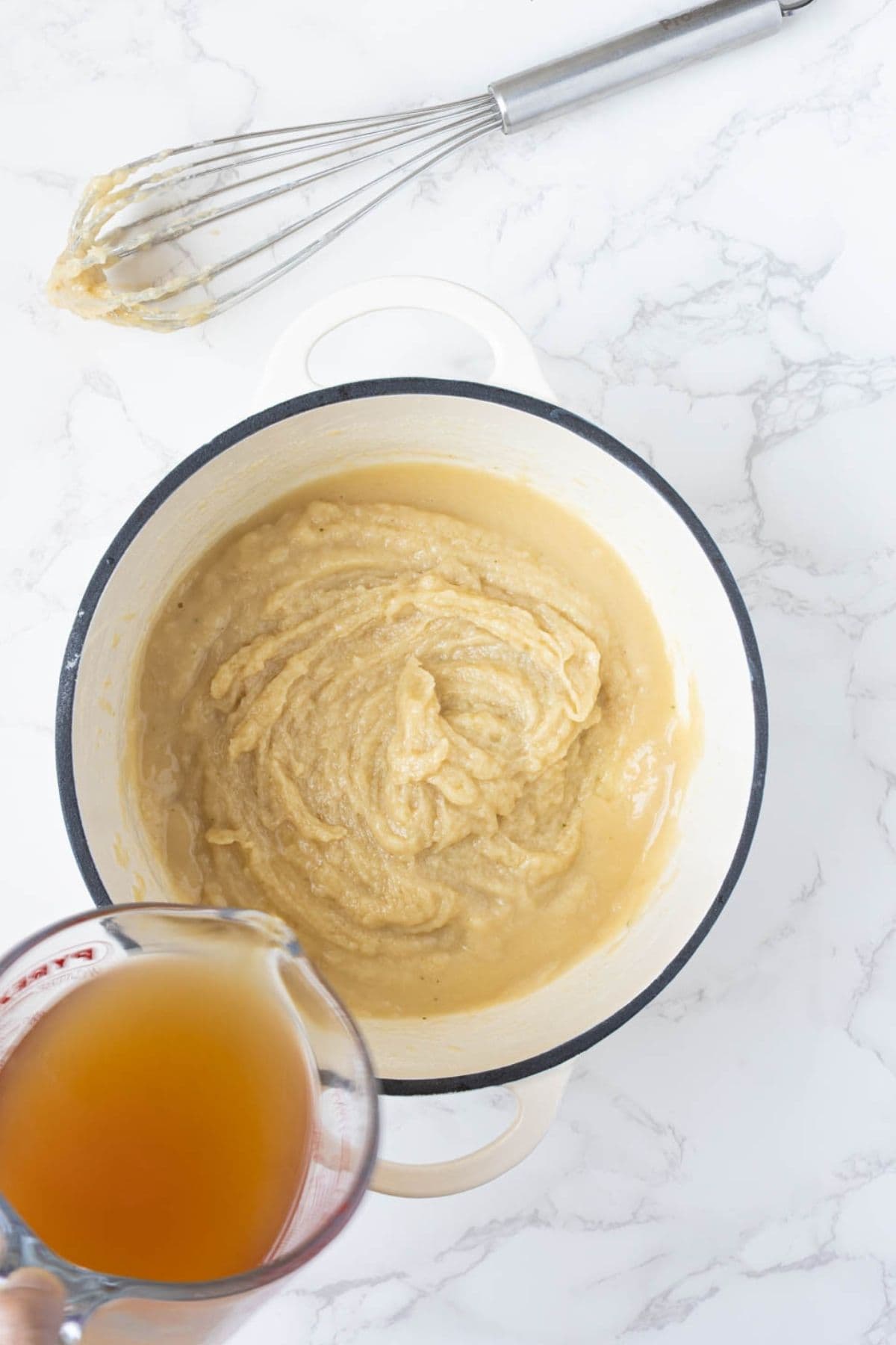 Adding stock to thick sourdough gravy roux while whisking.