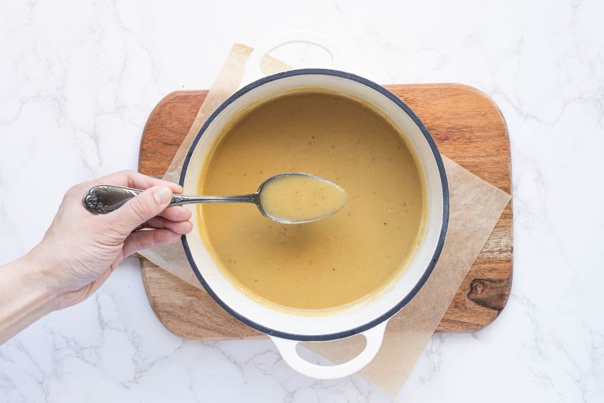 Homemade sourdough gravy in cooking pot topped with black pepper and ready to serve.