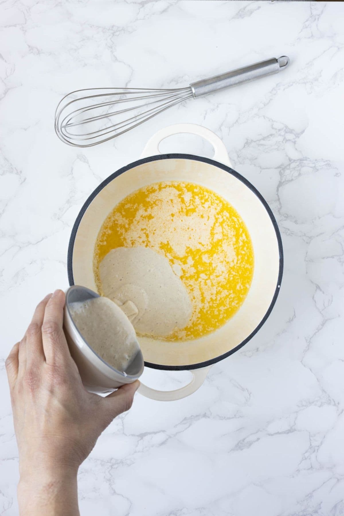 Melted butter and sourdough discard being added to a pot to make a roux for sourdough gravy.