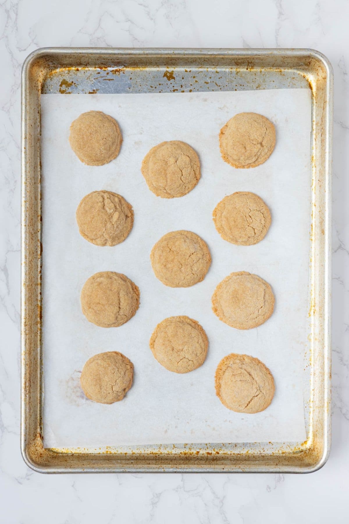 Freshly baked sourdough peanut butter cookies on a parchment-lined baking sheet before adding chocolate kisses.