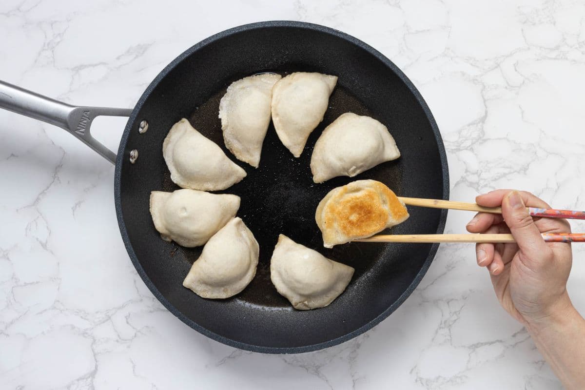 Browning the bottom of sourdough potstickers in a skillet.
