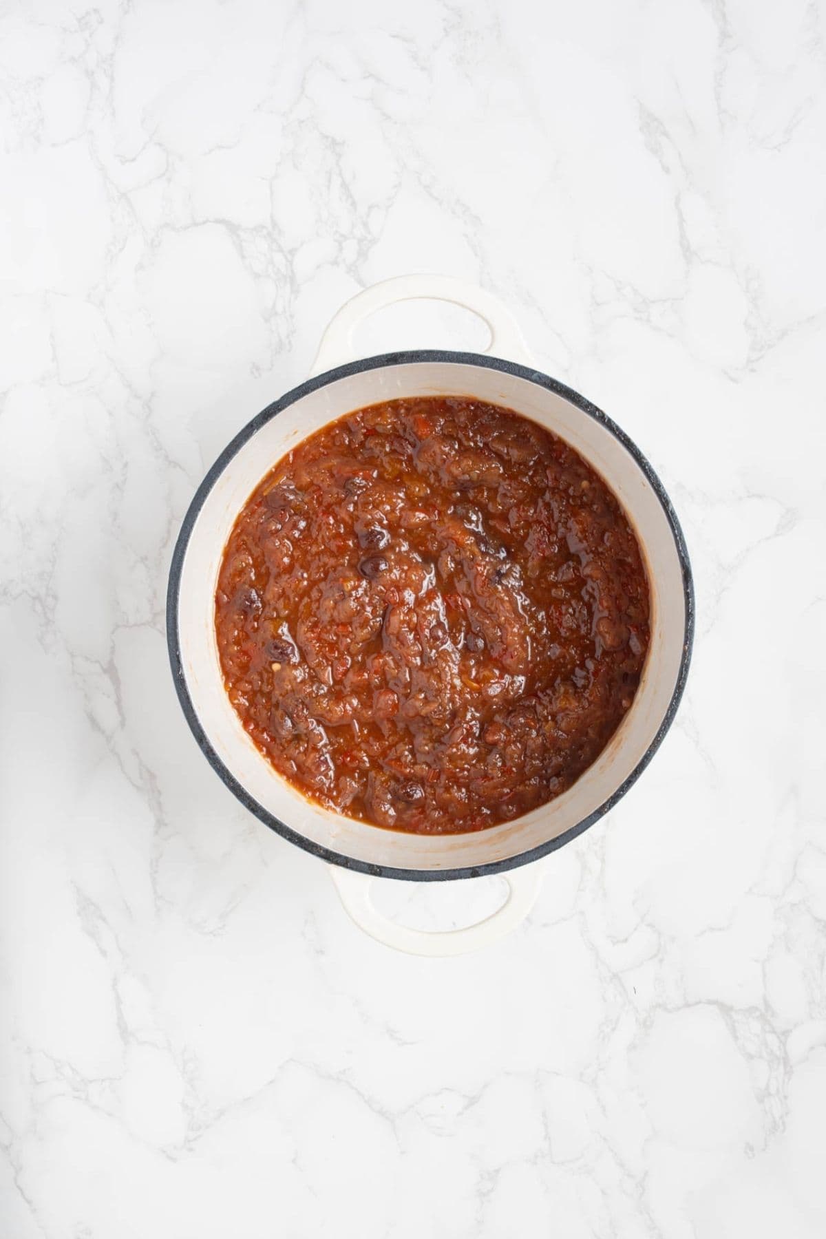Cooked summer fruits relish simmered until thick and glossy in a pot.