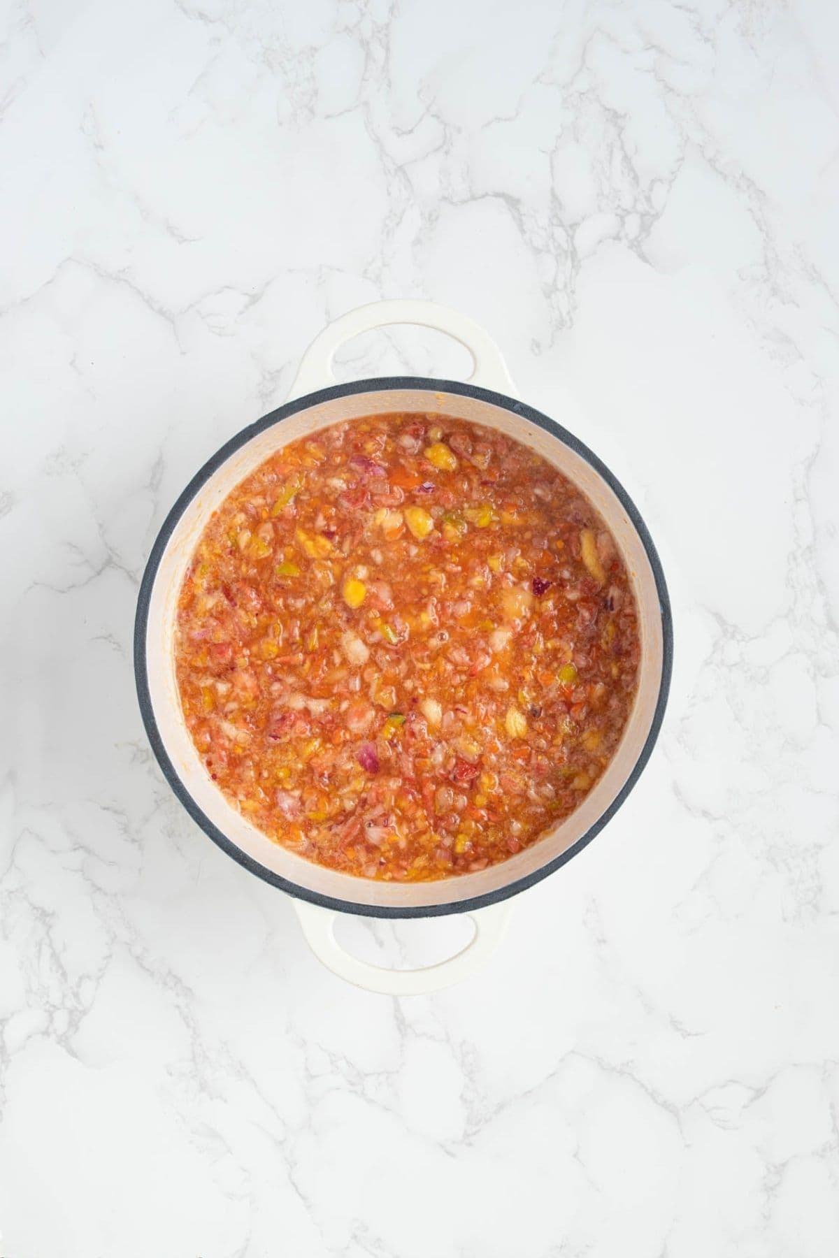 Summer fruits relish ingredients mixed together in a pot before cooking.