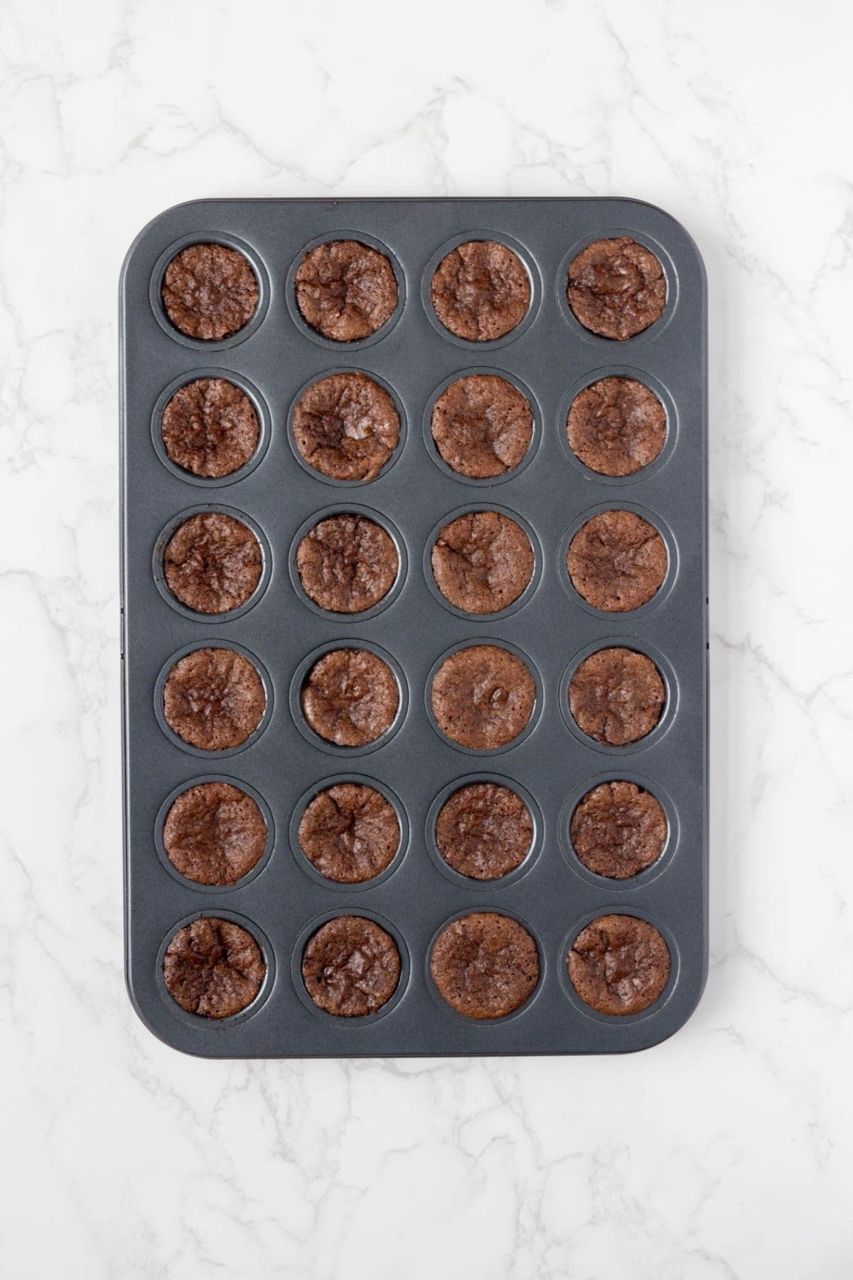 Freshly baked sourdough chocolate brownie bites cooling in a mini muffin pan.