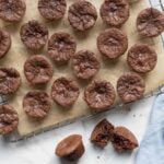 Sourdough chocolate brownie bites cooling on a wire rack with one brownie bite broken open to show the inside texture.