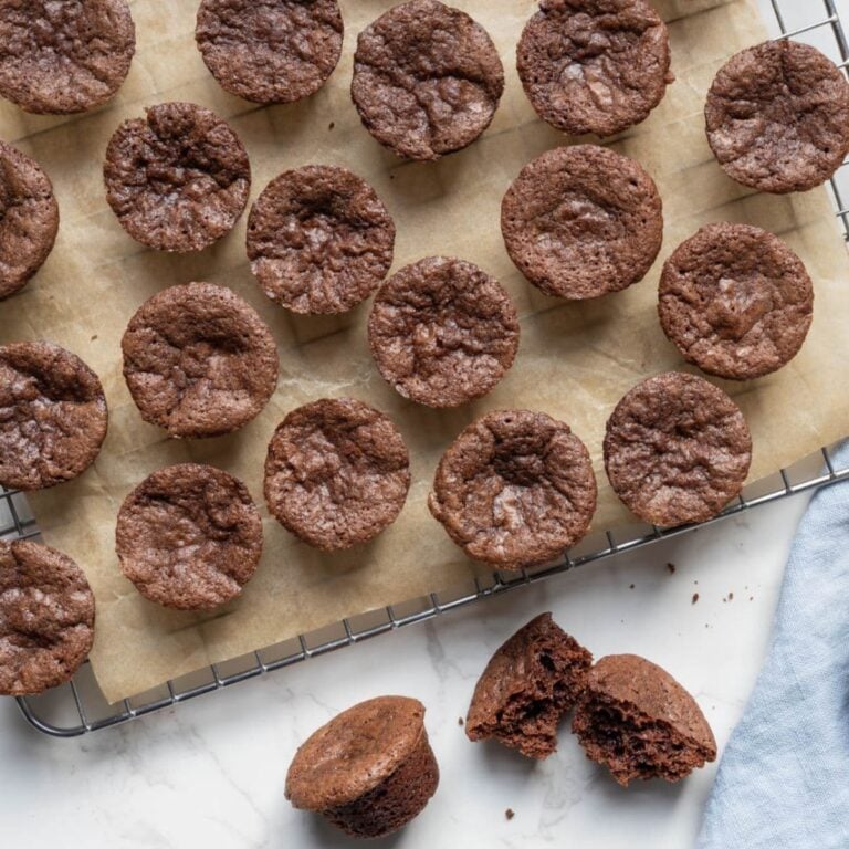 Sourdough chocolate brownie bites cooling on a wire rack with one brownie bite broken open to show the inside texture.