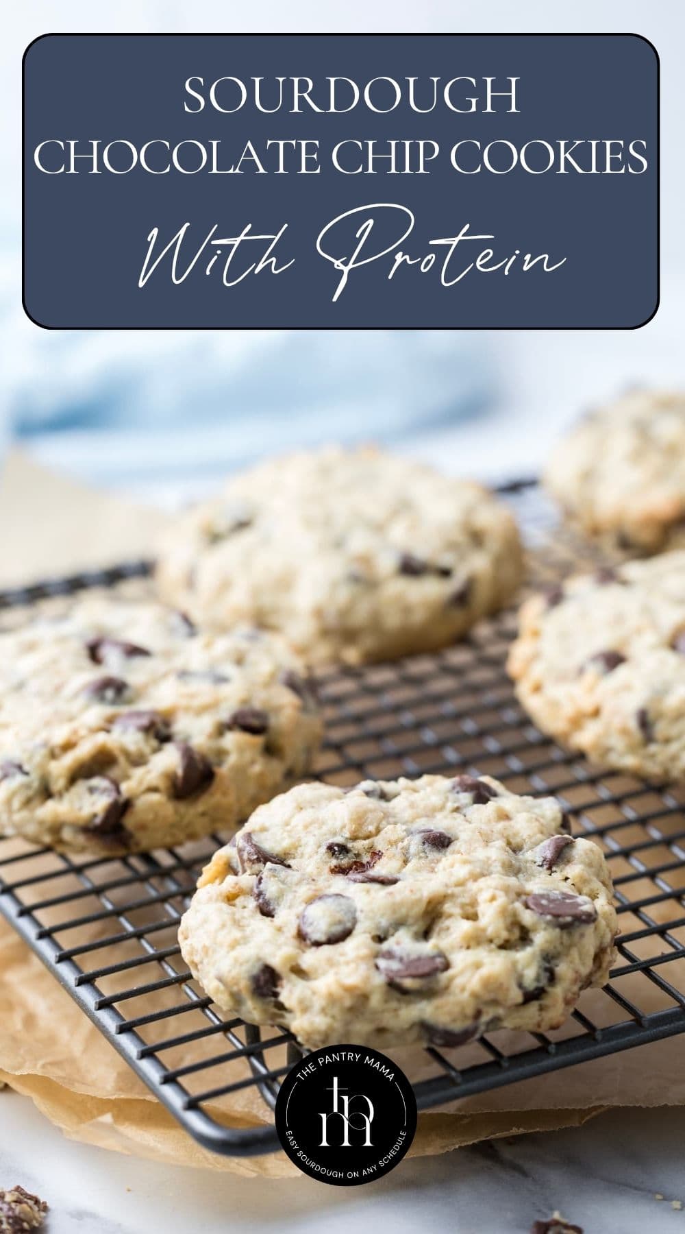 Protein sourdough chocolate chip cookies cooling on a wire rack with text overlay for a Pinterest Pin image.