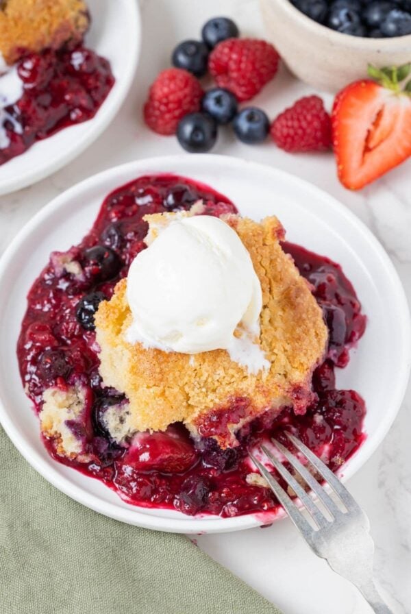 Serving of sourdough berry cobbler topped with vanilla ice cream on a dessert plate.