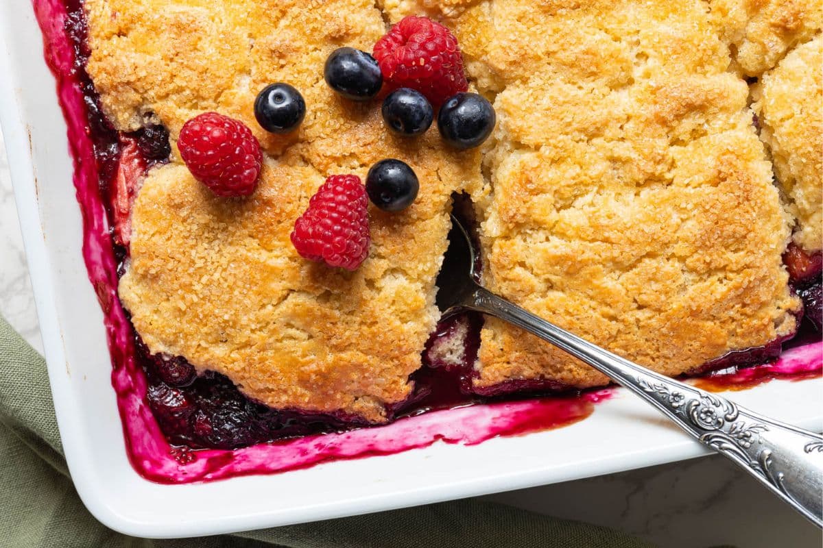 Close-up of sourdough berry cobbler showing biscuit-style topping over baked mixed berry filling.