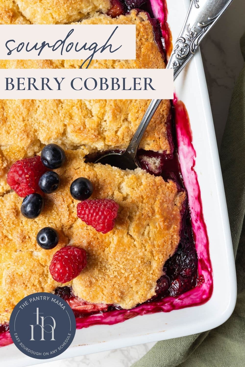 Close-up of sourdough berry cobbler with biscuit topping and baked berry filling in a casserole dish.