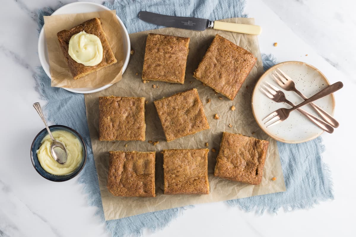 Overhead view of sourdough blondies arranged on parchment paper with cream cheese frosting for serving.