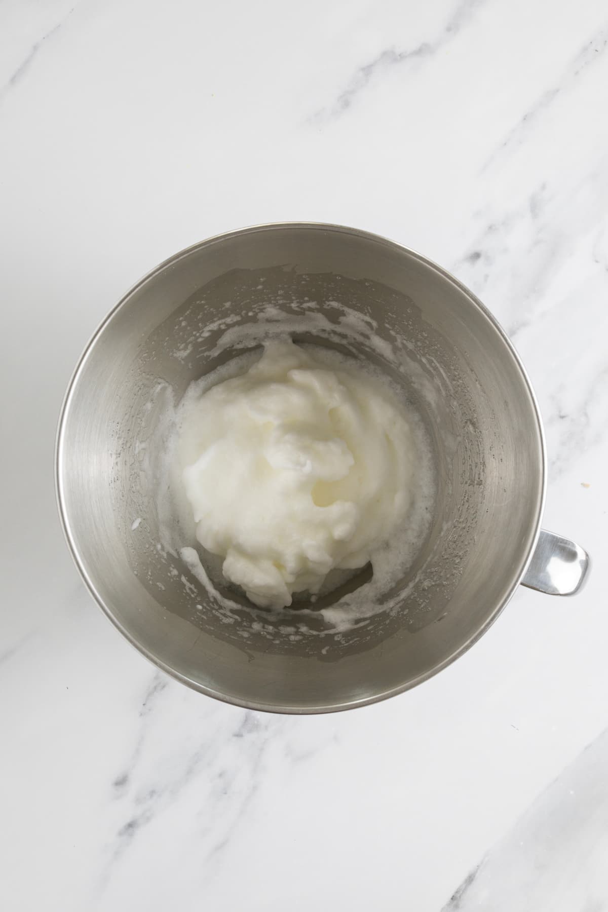 Egg whites whipped to soft peaks in the bowl of a stand mixer for sourdough blondies.