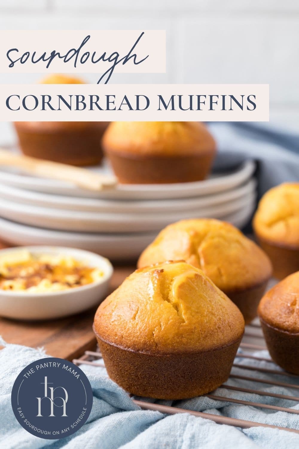 Sourdough cornbread muffins made with sourdough discard arranged on a cooling rack with plates, ready to serve.