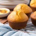 Freshly baked sourdough cornbread muffin topped with butter cooling on a wire rack.