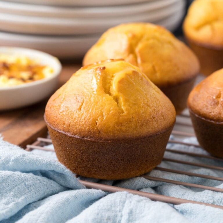 Freshly baked sourdough cornbread muffin topped with butter cooling on a wire rack.
