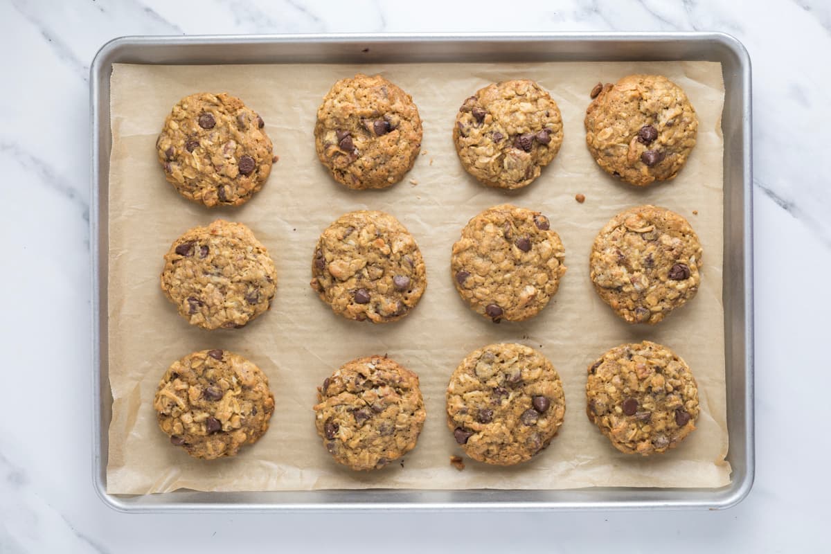 Freshly baked sourdough cowboy cookies on a parchment-lined baking sheet.