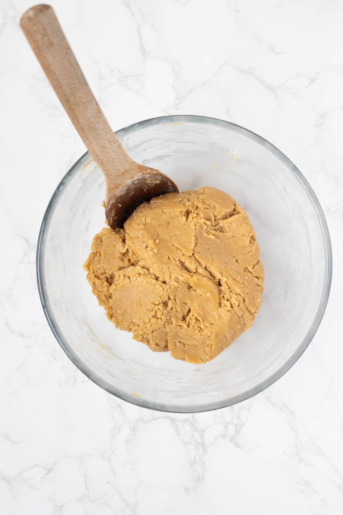 Finished sourdough peanut butter cookie dough in a glass mixing bowl ready for shaping.