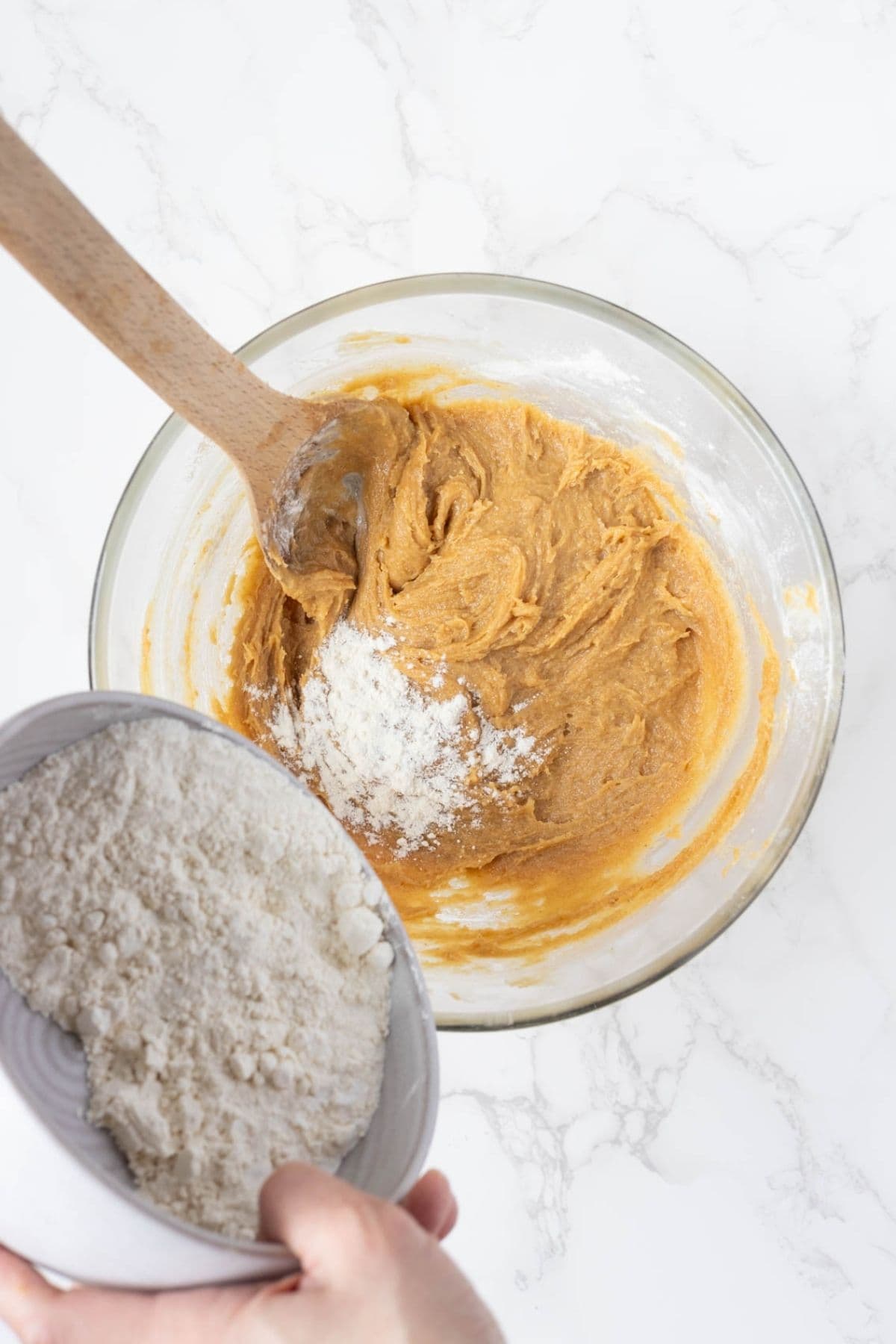 Flour being added to peanut butter cookie dough while making sourdough discard peanut butter cookies.
