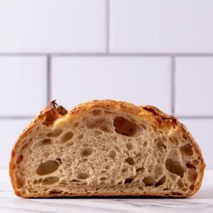A photo taken front on of a loaf of sourdough bread sliced open through the middle so you can see the crumb inside.