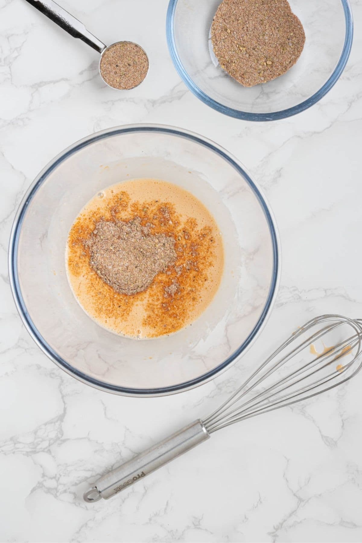 Bowl of sourdough discard, egg, and spices being prepared for sourdough fried chicken marinade.