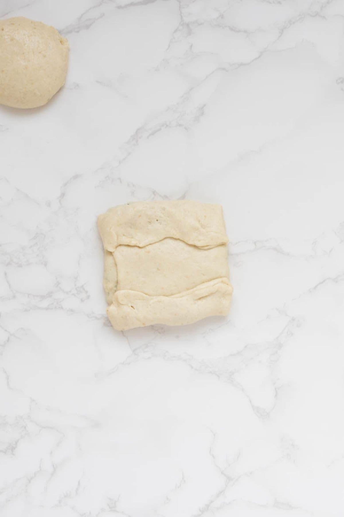 Sourdough gozleme dough folded and sealed around spinach and feta filling.