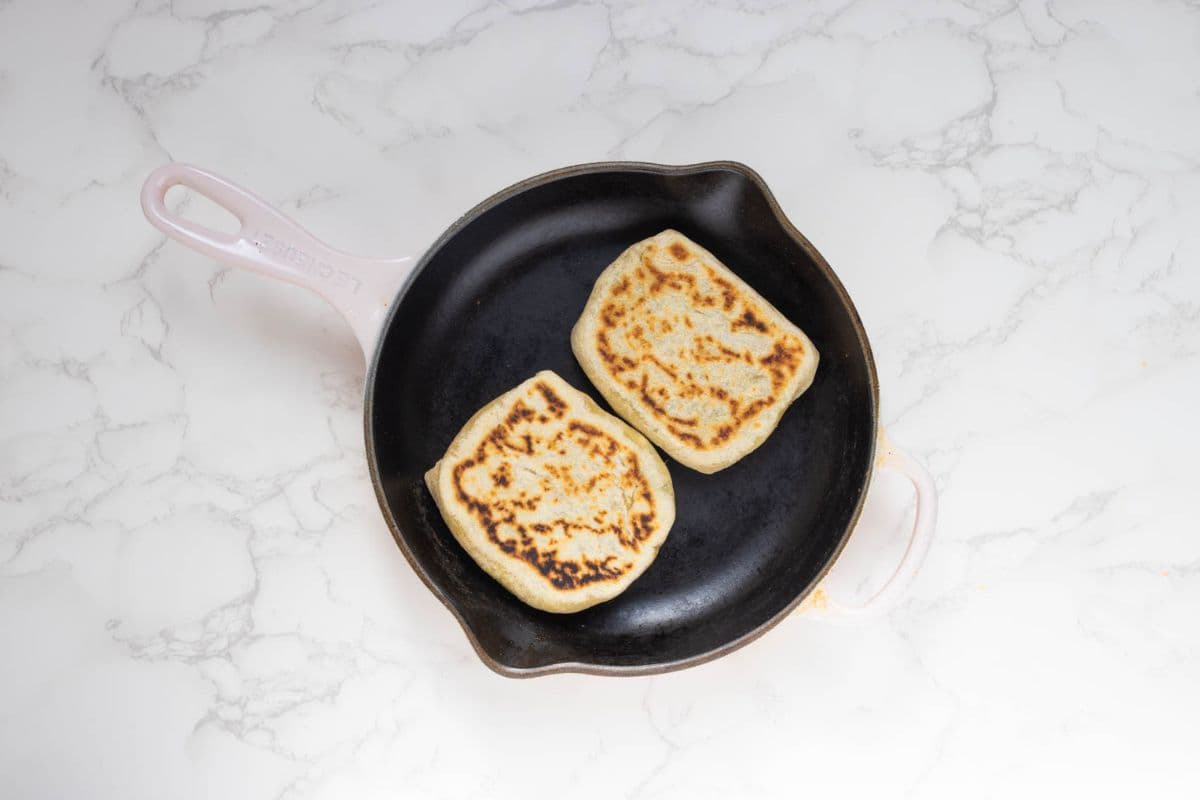 Two sourdough gozleme cooking in a skillet until golden and crisp.