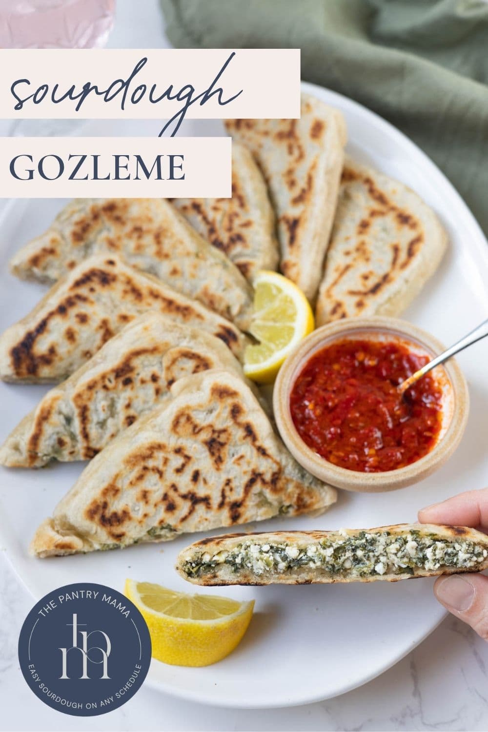 Homemade sourdough gozleme stuffed with spinach and feta and served with chili sauce for dipping and showing one cut open.