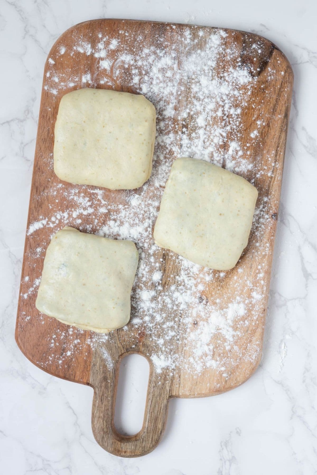Filled sourdough gozleme shaped into squares and dusted with flour before cooking.