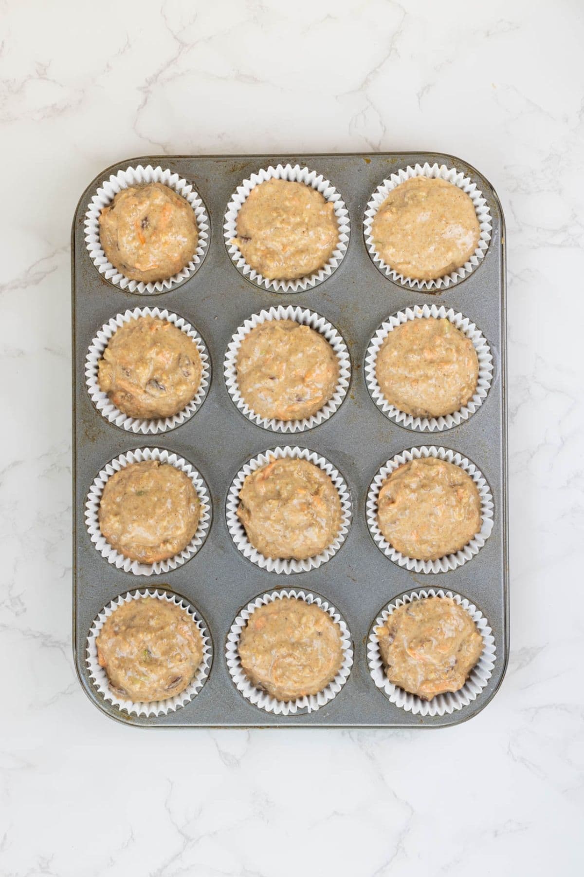 Sourdough morning glory muffin batter portioned into lined muffin cups ready for baking.