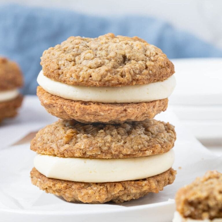 Two stacked sourdough oatmeal cream pies with thick vanilla filling on a white plate.