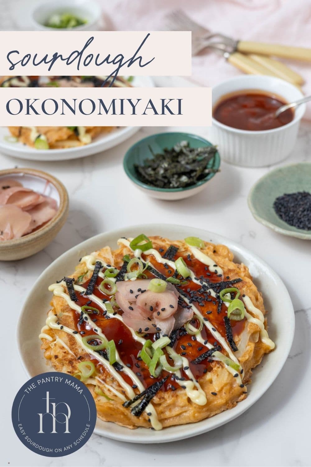 Sourdough okonomiyaki Japanese pancakes served with traditional toppings including pickled ginger, scallions, sesame seeds, nori, mayonnaise, and savory sauce and text overlay for a Pinterest pin image.