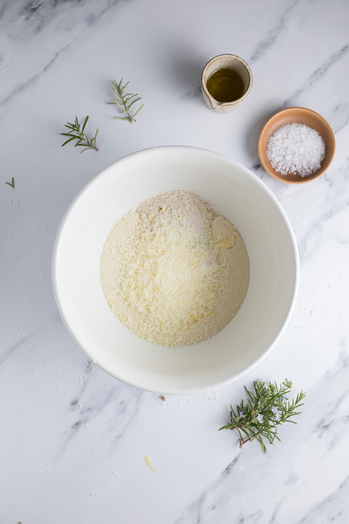 Ingredients in a mixing bowl to make sourdough parmesan rosemary cracker dough.