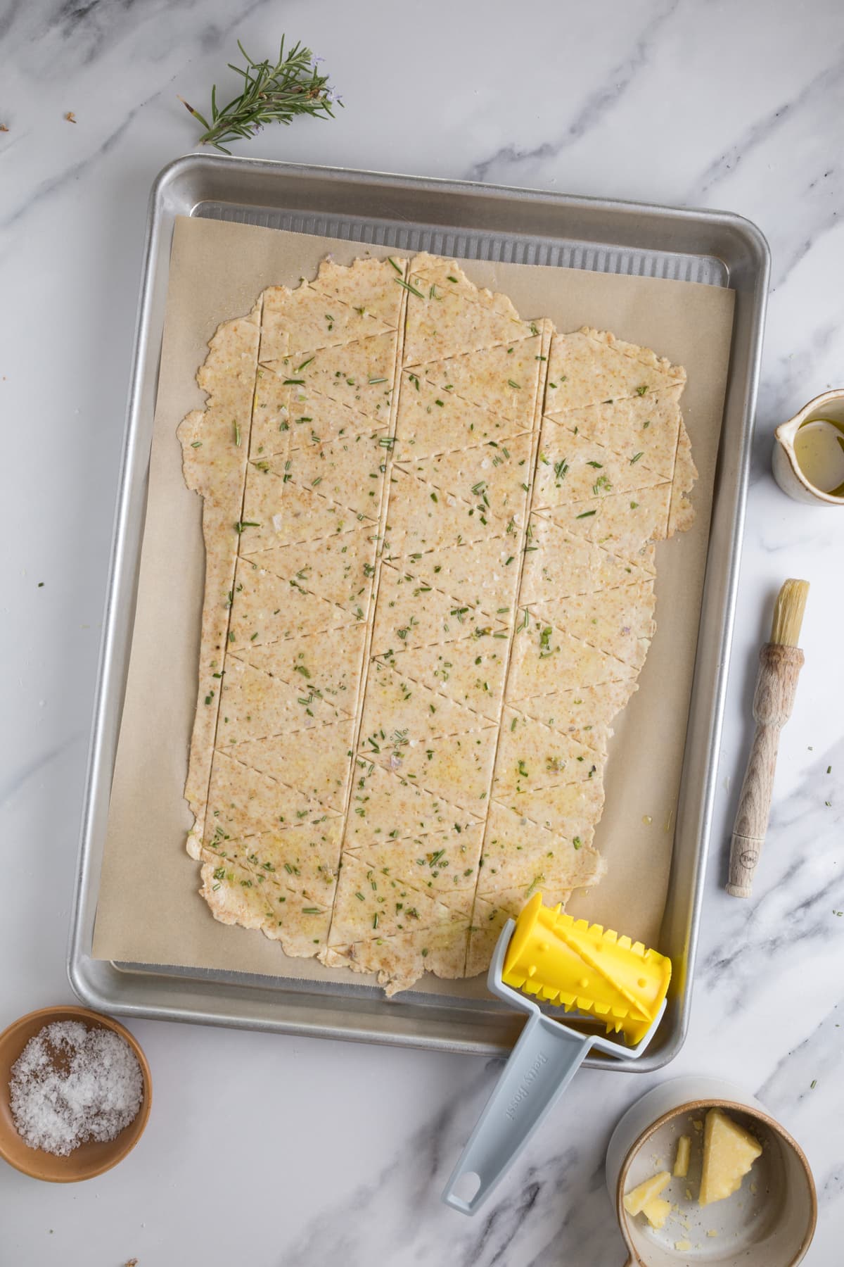 Sourdough cracker dough with rosemary, before adding parmesan cheese, scored into triangles before baking.