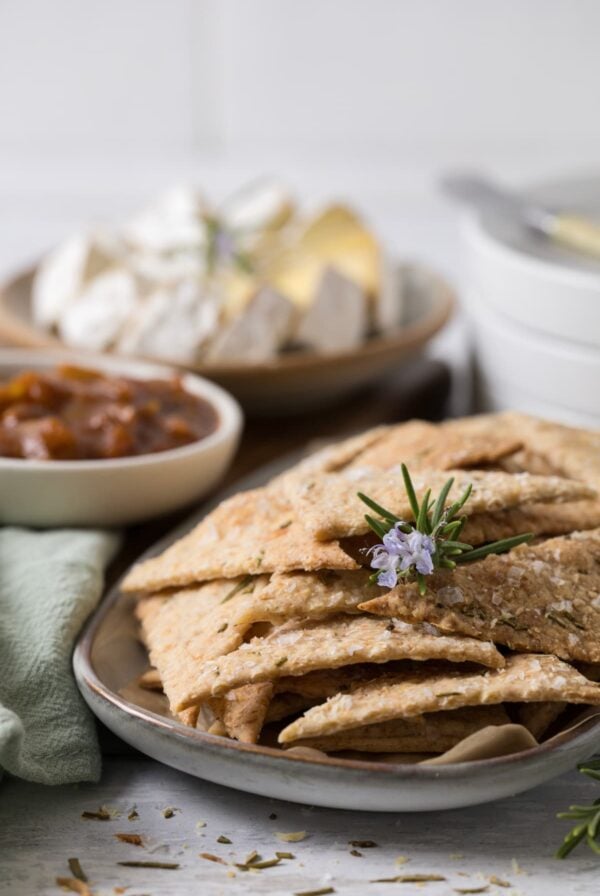 Sourdough parmesan rosemary crackers served on a platter with a cheese board and chutney.