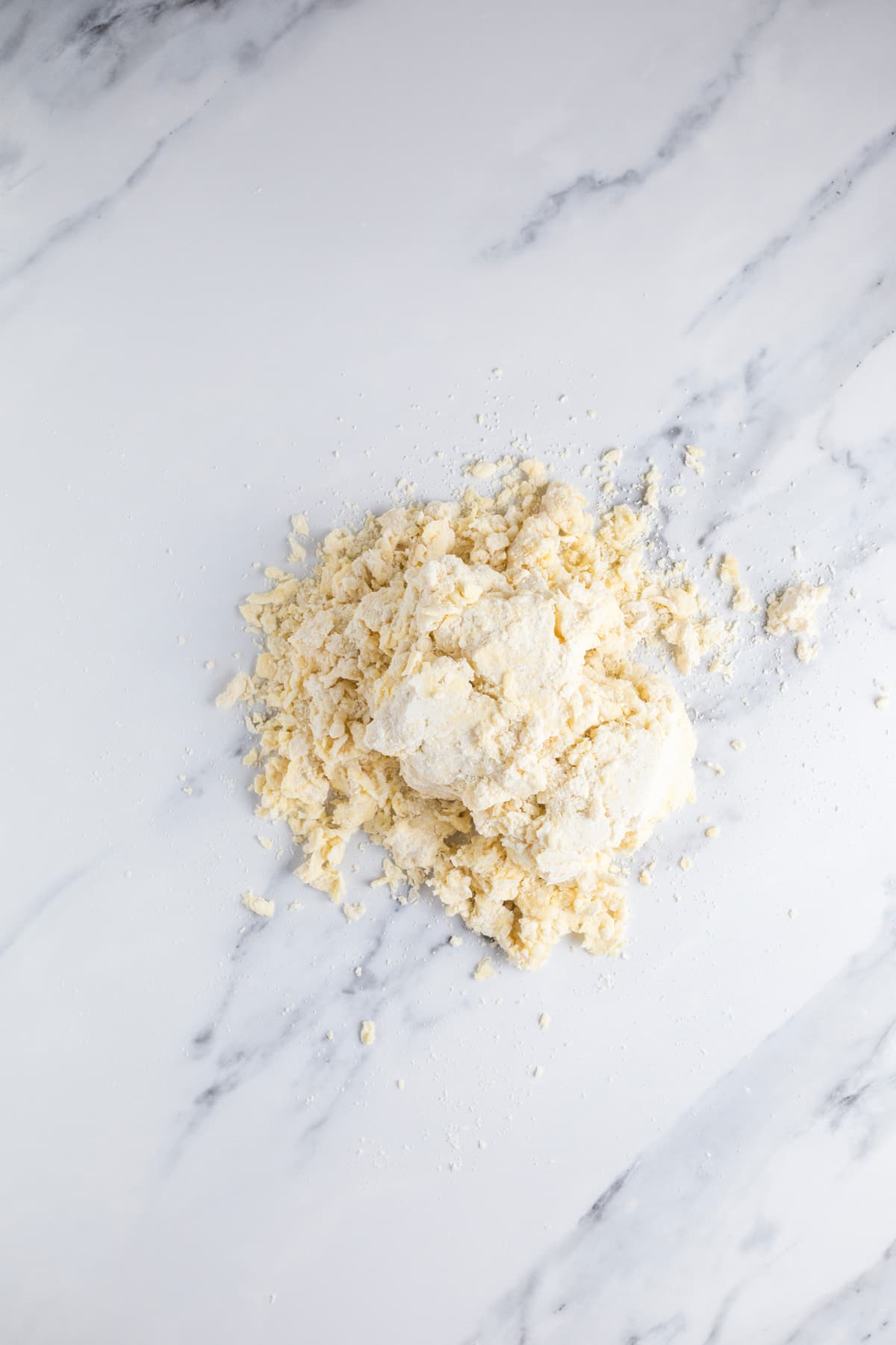 Crumbly sourdough pie crust dough tipped onto a work surface ready to be shaped.