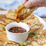 Crispy sourdough scallion pancakes arranged around a bowl of chili dipping sauce.