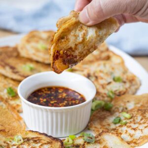 Crispy sourdough scallion pancakes arranged around a bowl of chili dipping sauce.