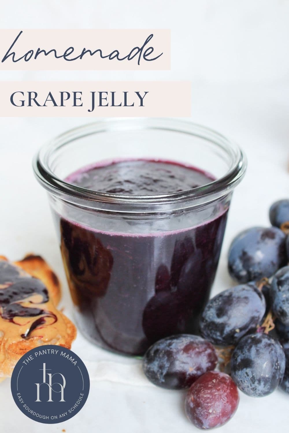 Jar of homemade grape jelly beside fresh grapes with text overlay reading "Homemade Grape Jelly."