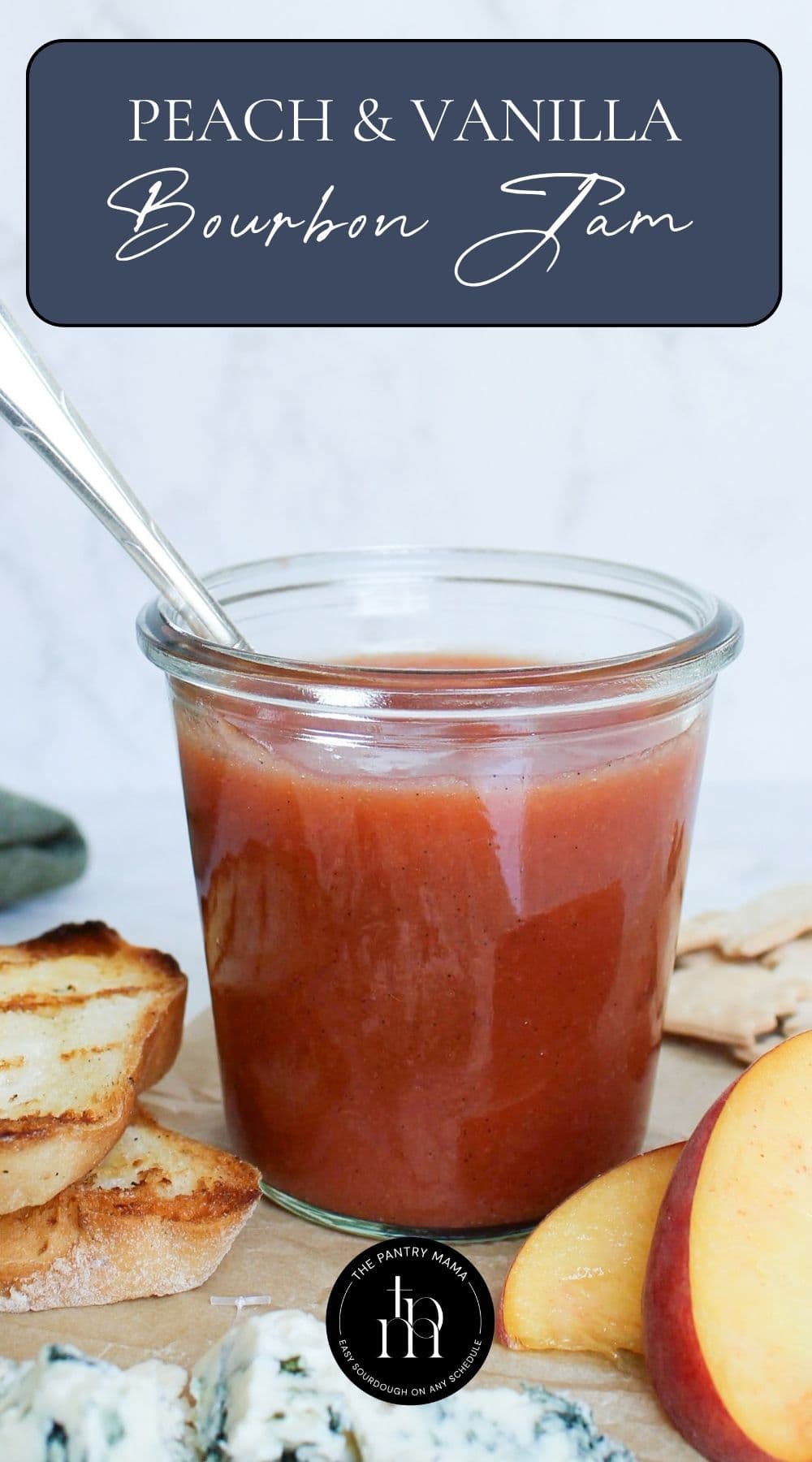 Peach vanilla bourbon jam in a glass jar served with toasted sourdough bread, peaches, sourdough crackers, and blue cheese.