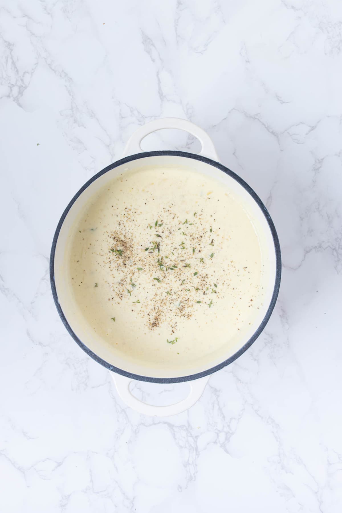 Creamy sourdough cheese sauce seasoned in a pot before adding the potatoes.