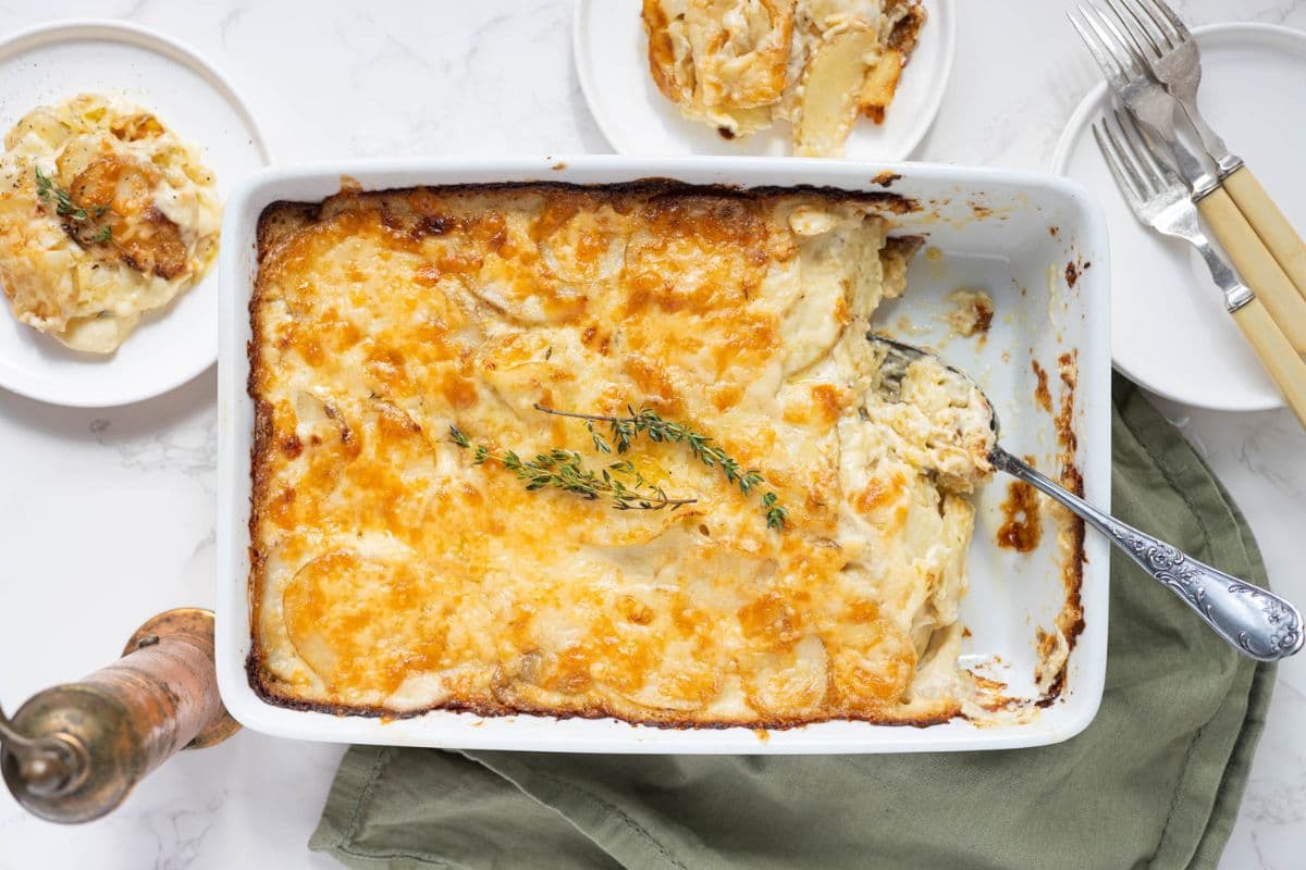 Freshly baked sourdough au gratin potatoes in a casserole dish on the table for serving.