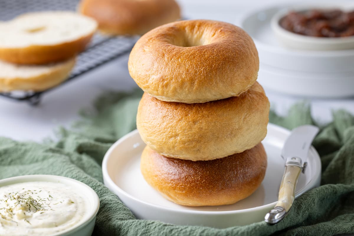 Stack of homemade sourdough bagels with a shiny golden crust, ready to serve with cream cheese.