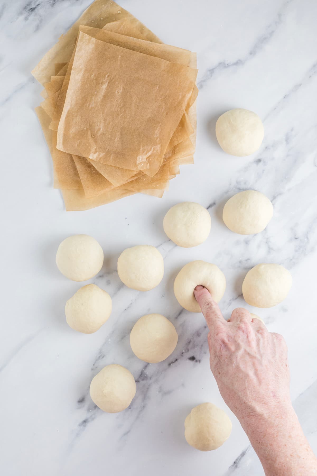 Pressing a finger through a dough ball to create the center hole for a sourdough bagel.